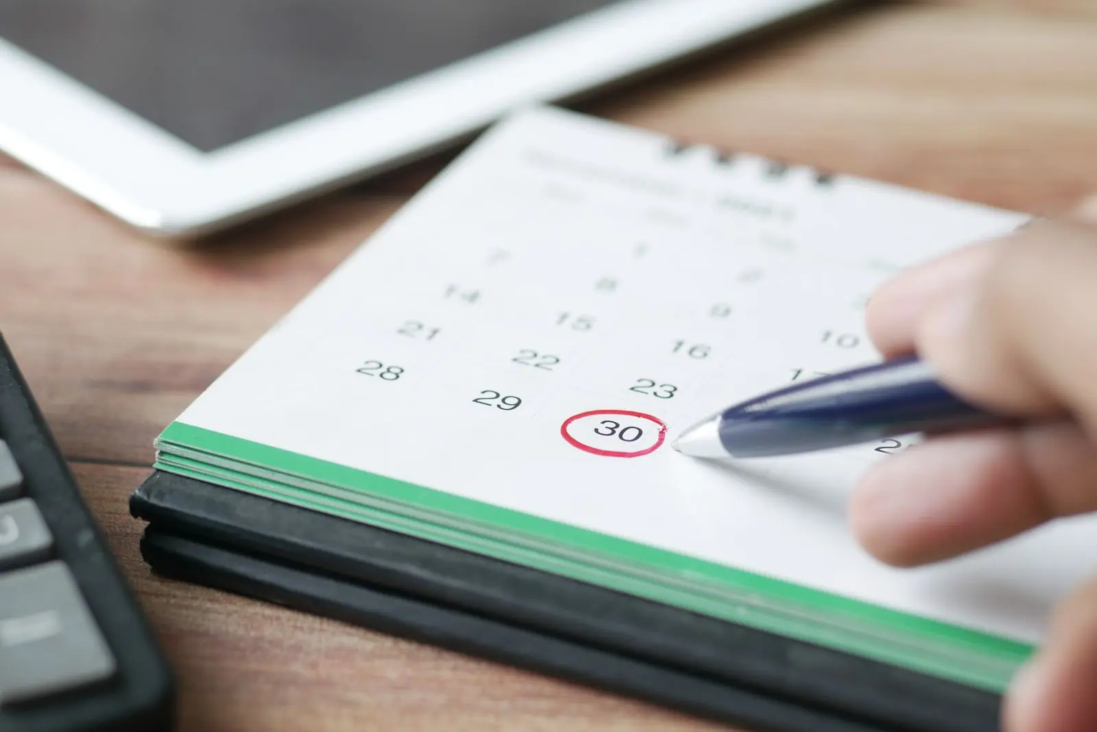 Mano marcando un día en un calendario de sobremesa en la oficina