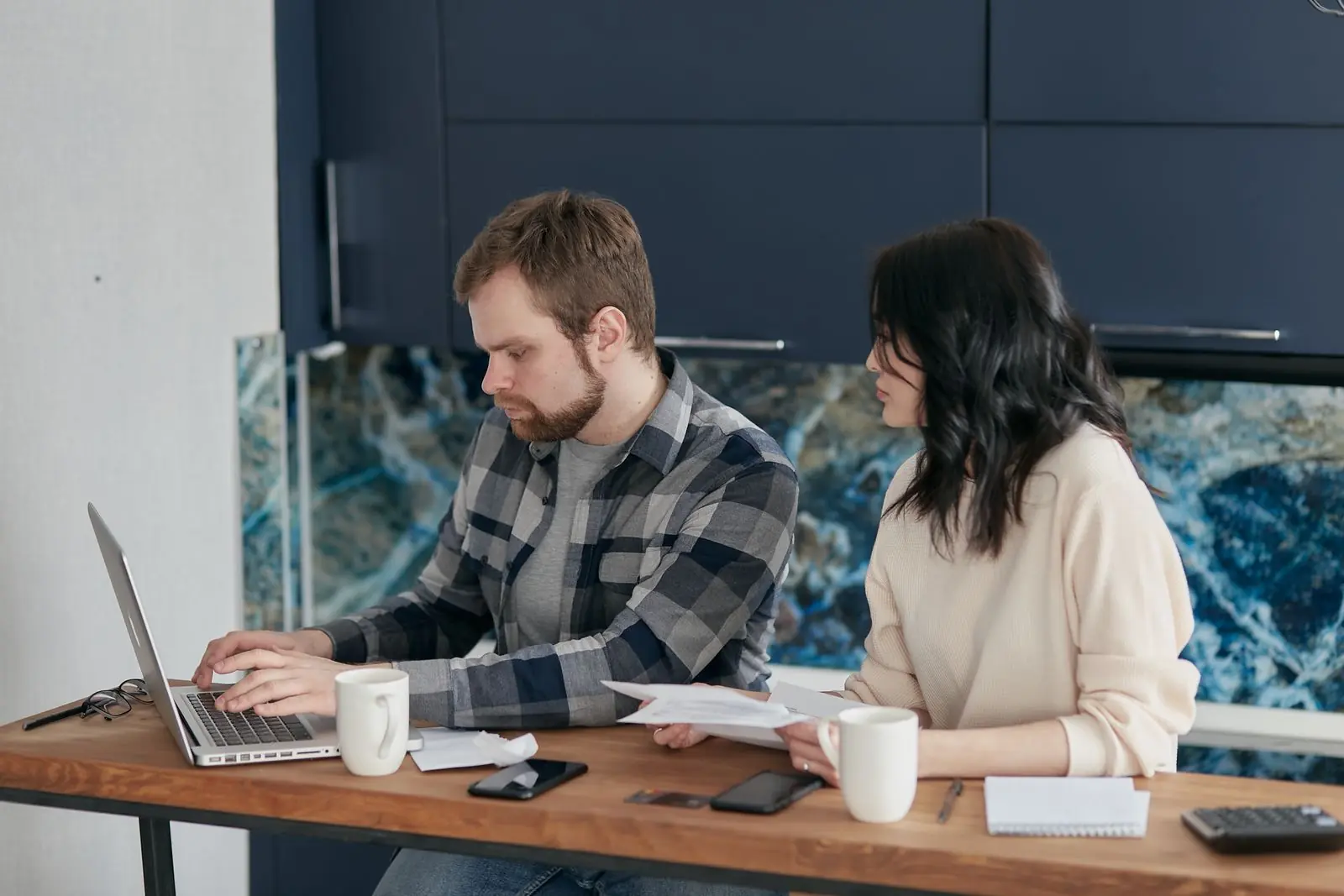 Pareja de autónomos revisando facturas con un portátil